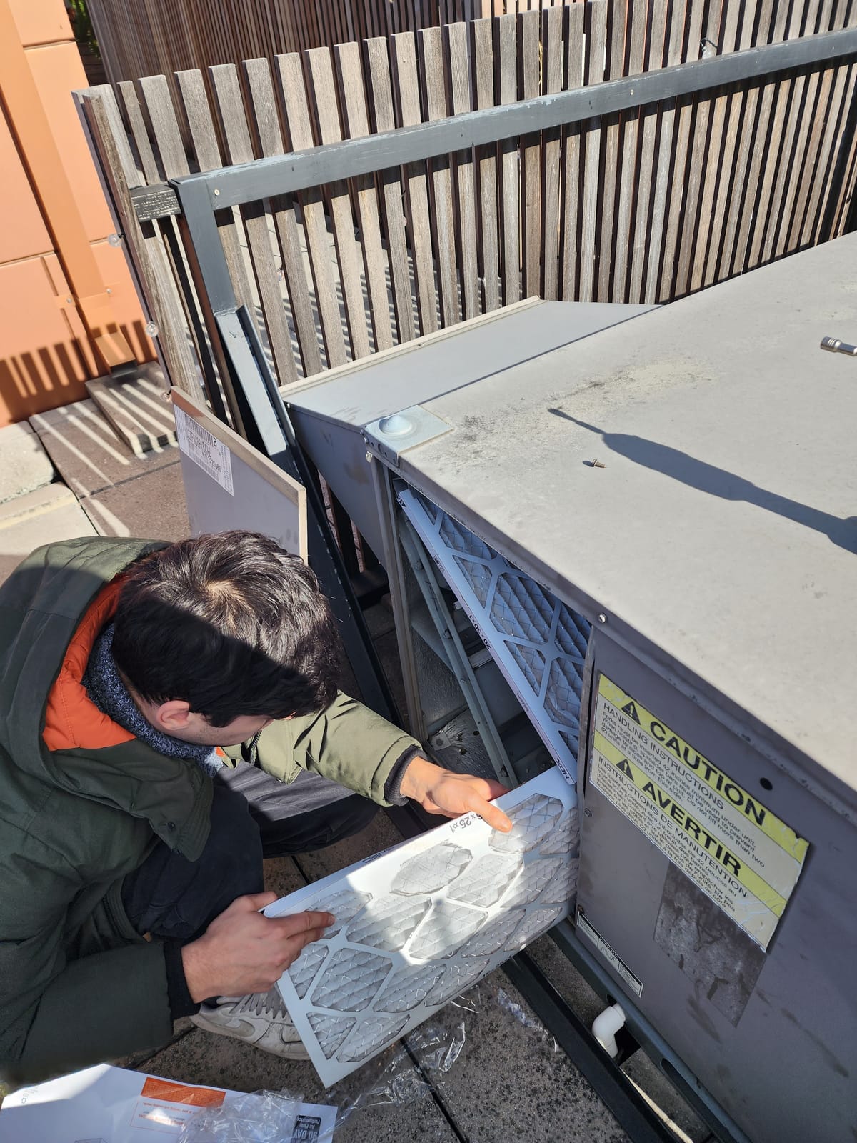 Technician replacing air filter on rooftop unit